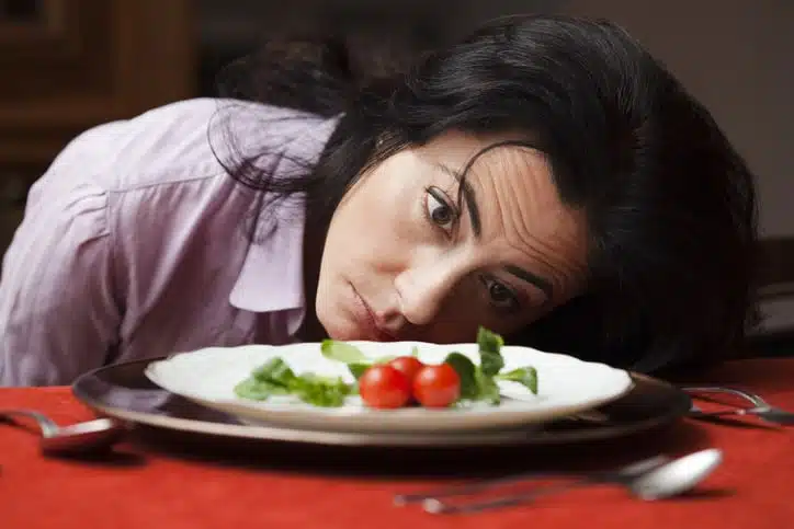 Woman sitting at a table with a plate of salad